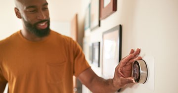 man adjusting smart thermostat